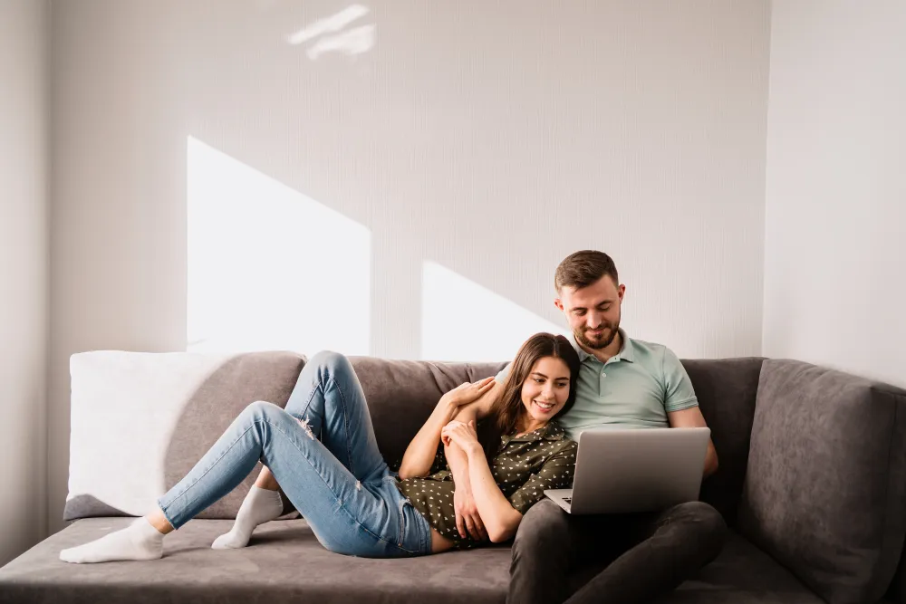 Mann und Frau sitzen mit einem Laptop auf dem Sofa